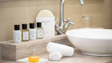Un tocador de baño con un lavabo blanco, un espejo y tres botellas de exfoliante corporal.