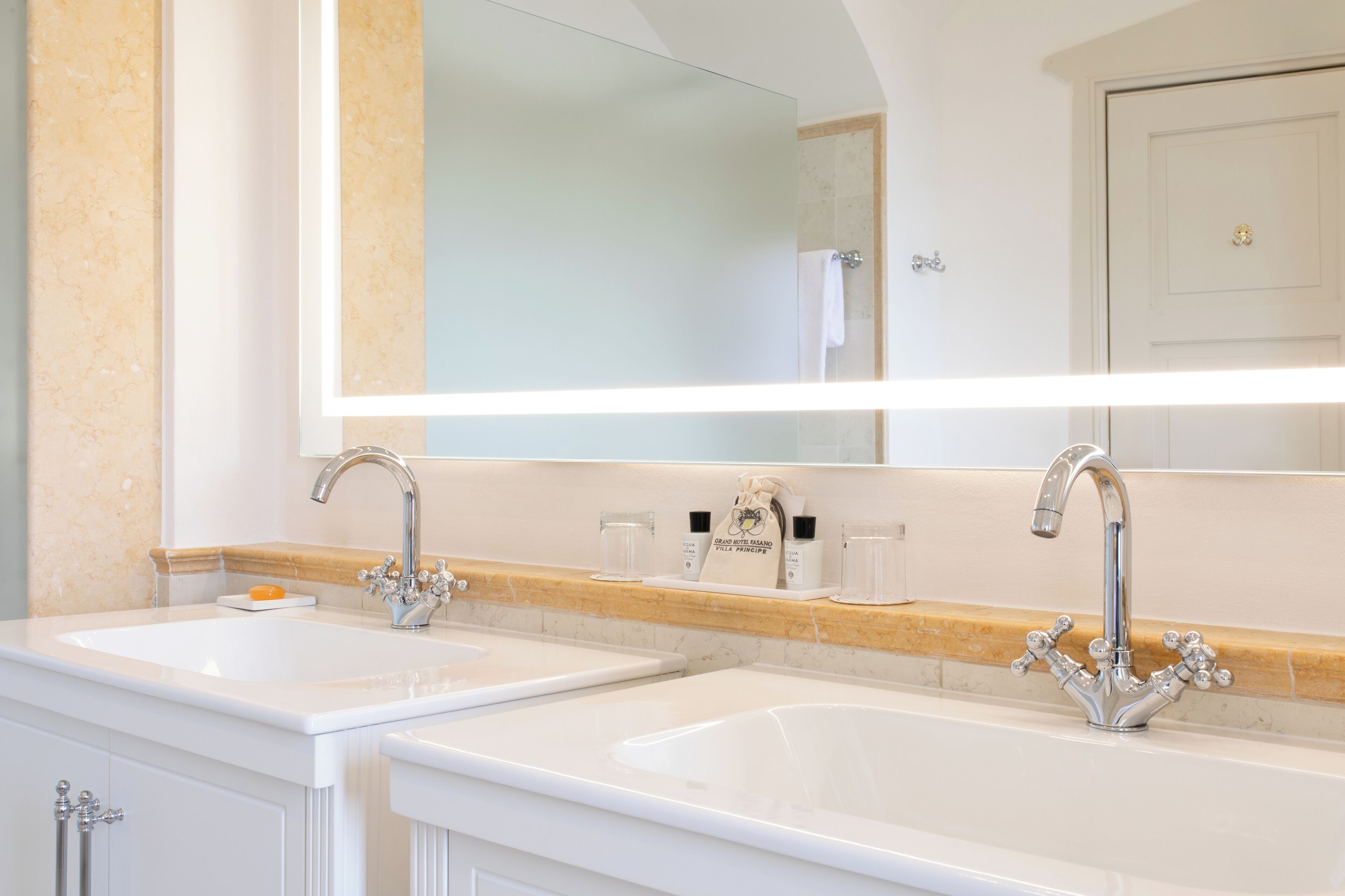 Un baño con dos lavamanos, un espejo grande y un perchero para toallas.