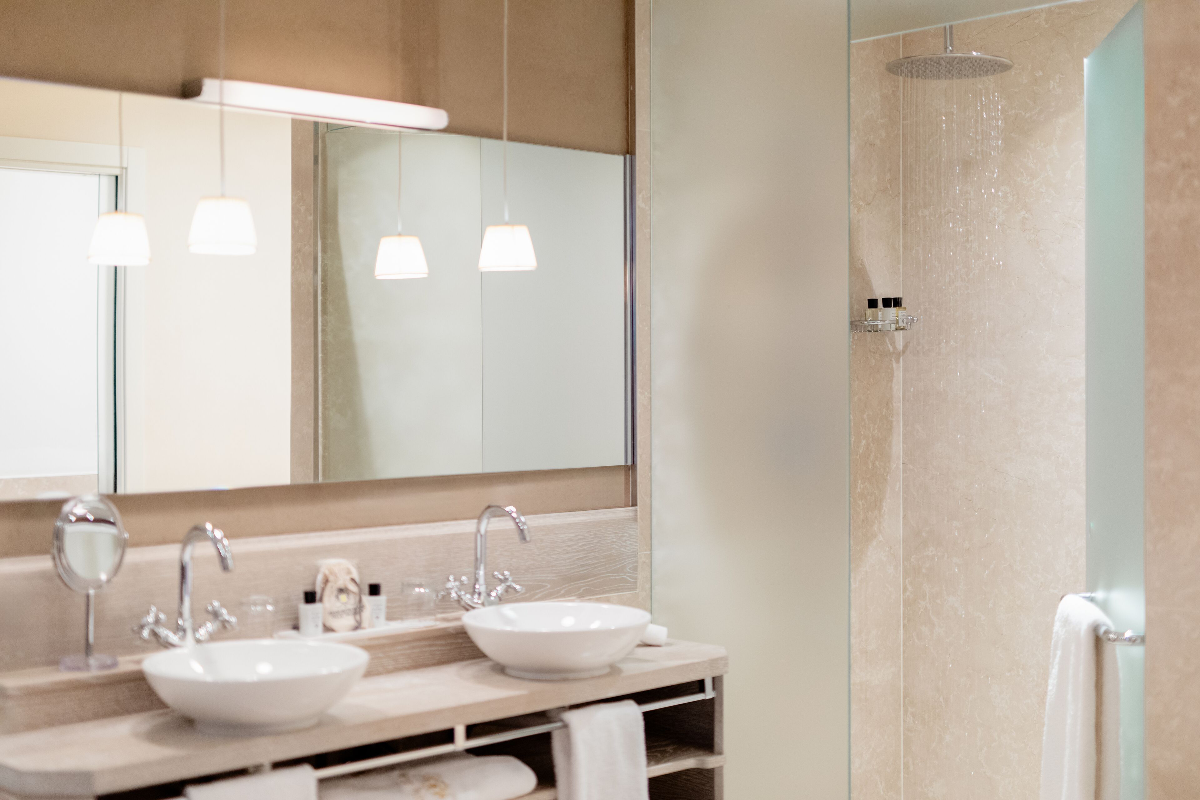 Een moderne badkamer met een grote spiegel, twee wastafels en een douche.