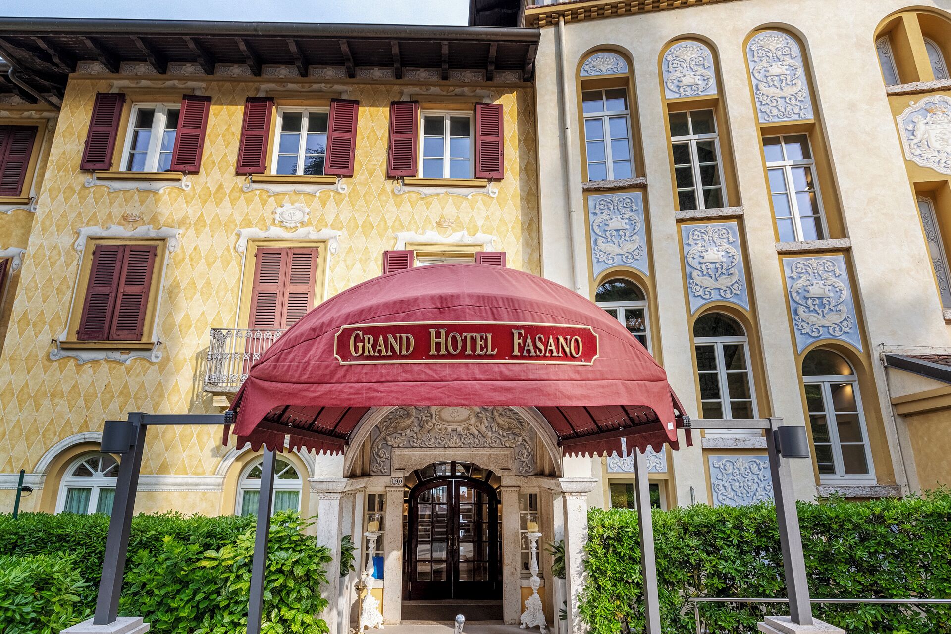La entrada del Grand Hotel Fasano, con un llamativo toldo rojo y detalles arquitectónicos ornamentados.