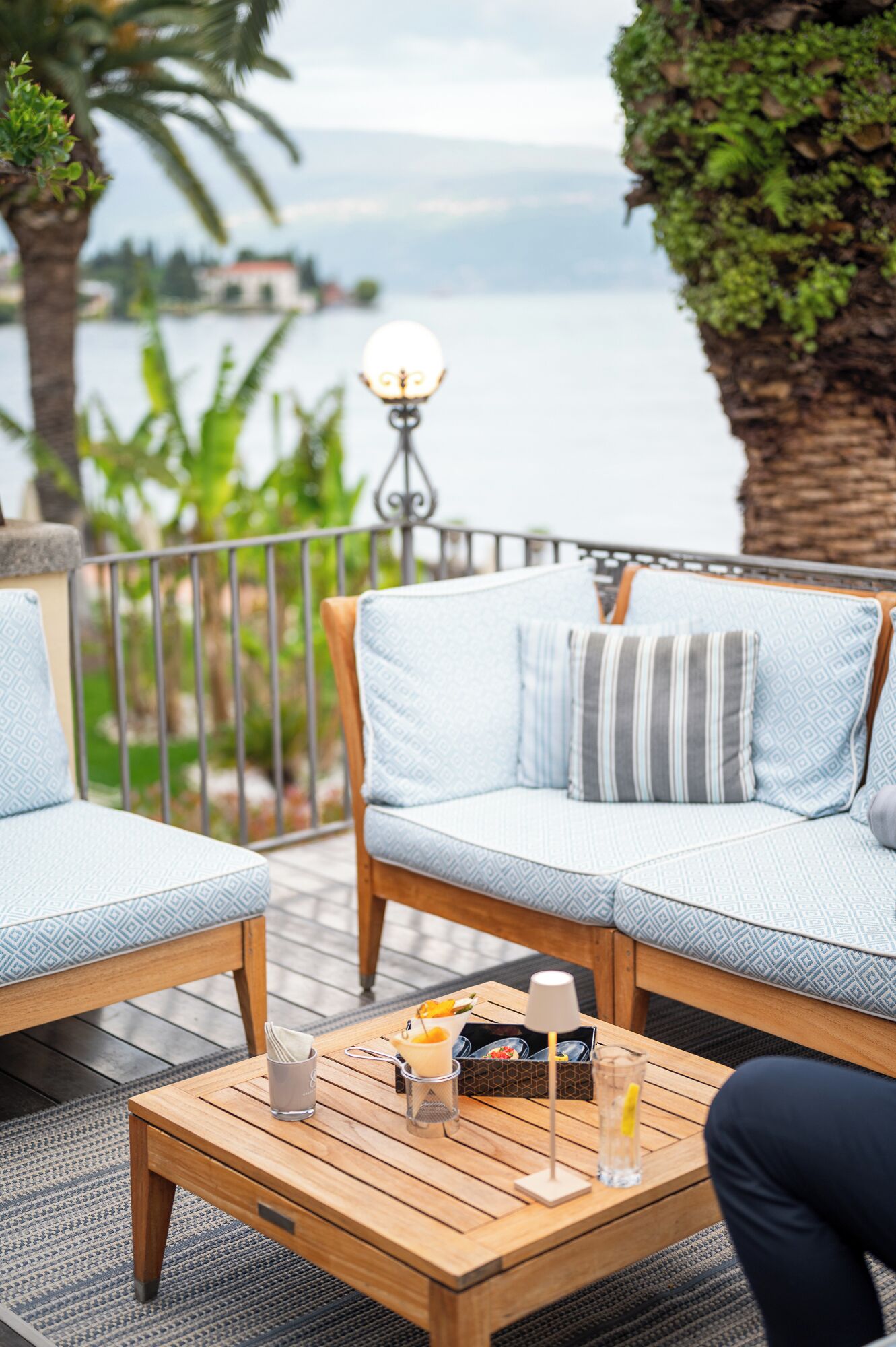 A wooden deck with a sofa and armchairs, a coffee table, and a lamp.