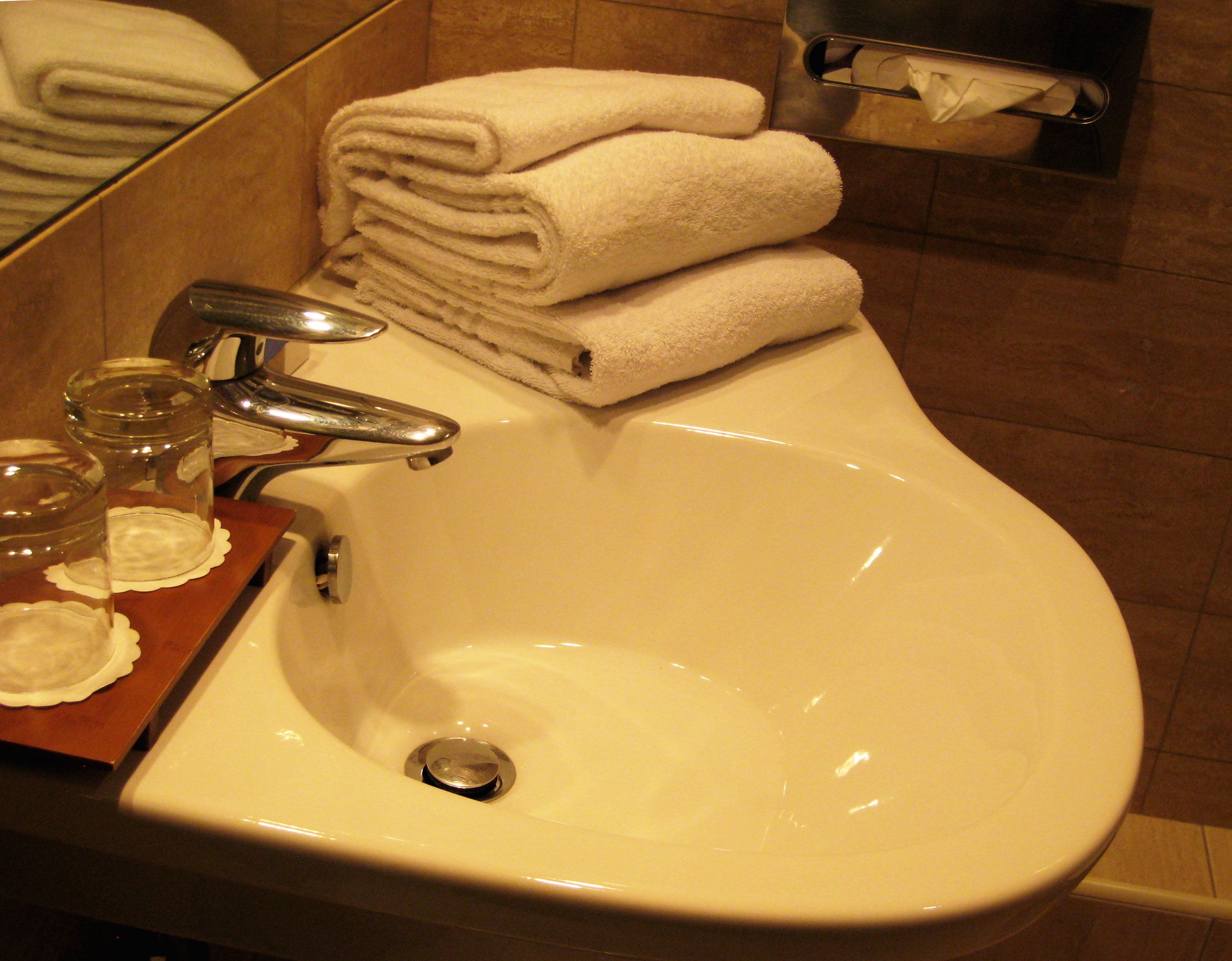 Un lavabo dans la salle de bain avec un miroir, un porte-serviettes avec des serviettes pliées et une boîte de mouchoirs.