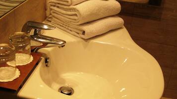 Un lavabo dans la salle de bain avec un miroir, un porte-serviettes avec des serviettes pliées et une boîte de mouchoirs.