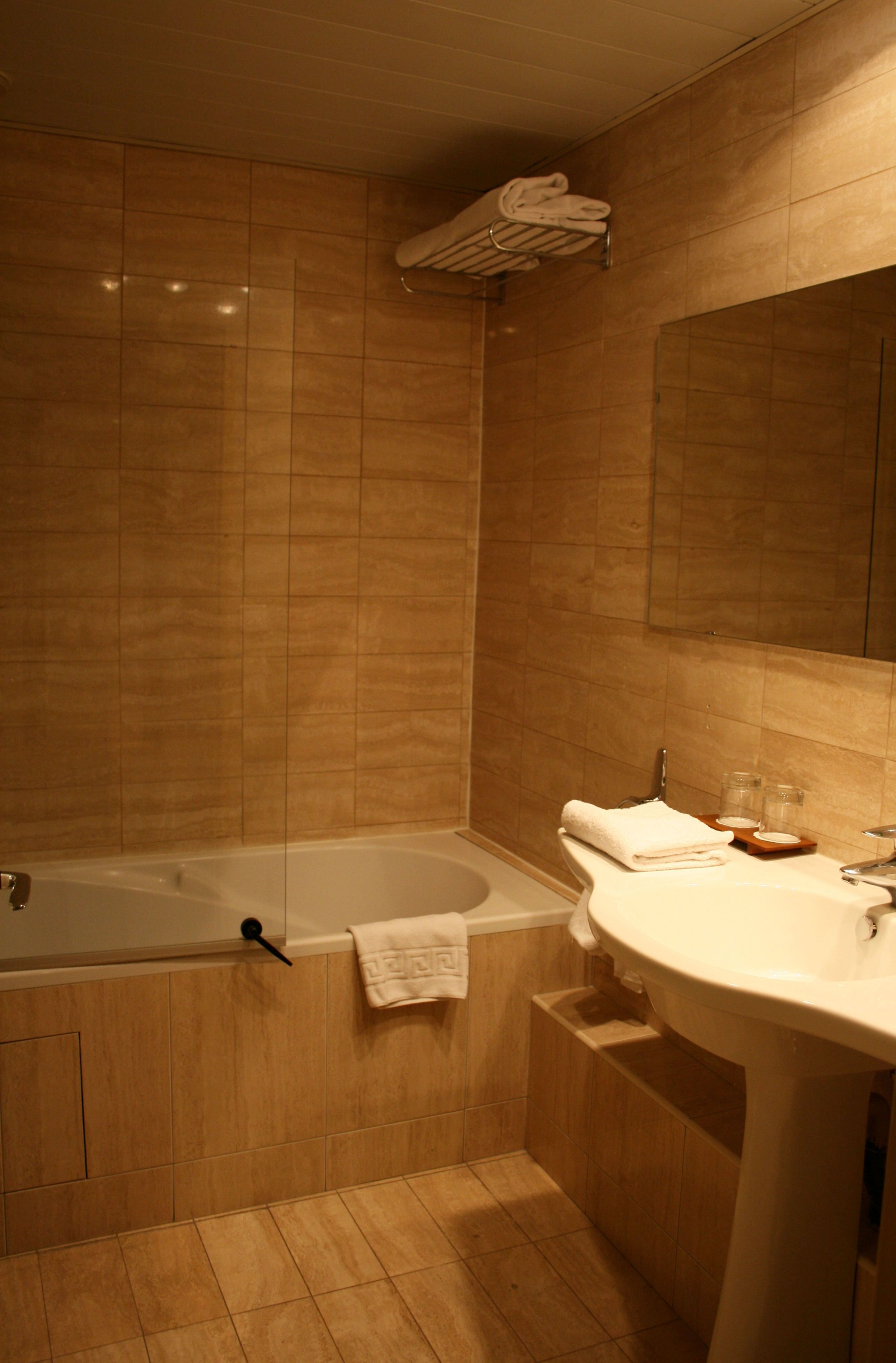 A bathroom with a bathtub, a sink, and a mirror.