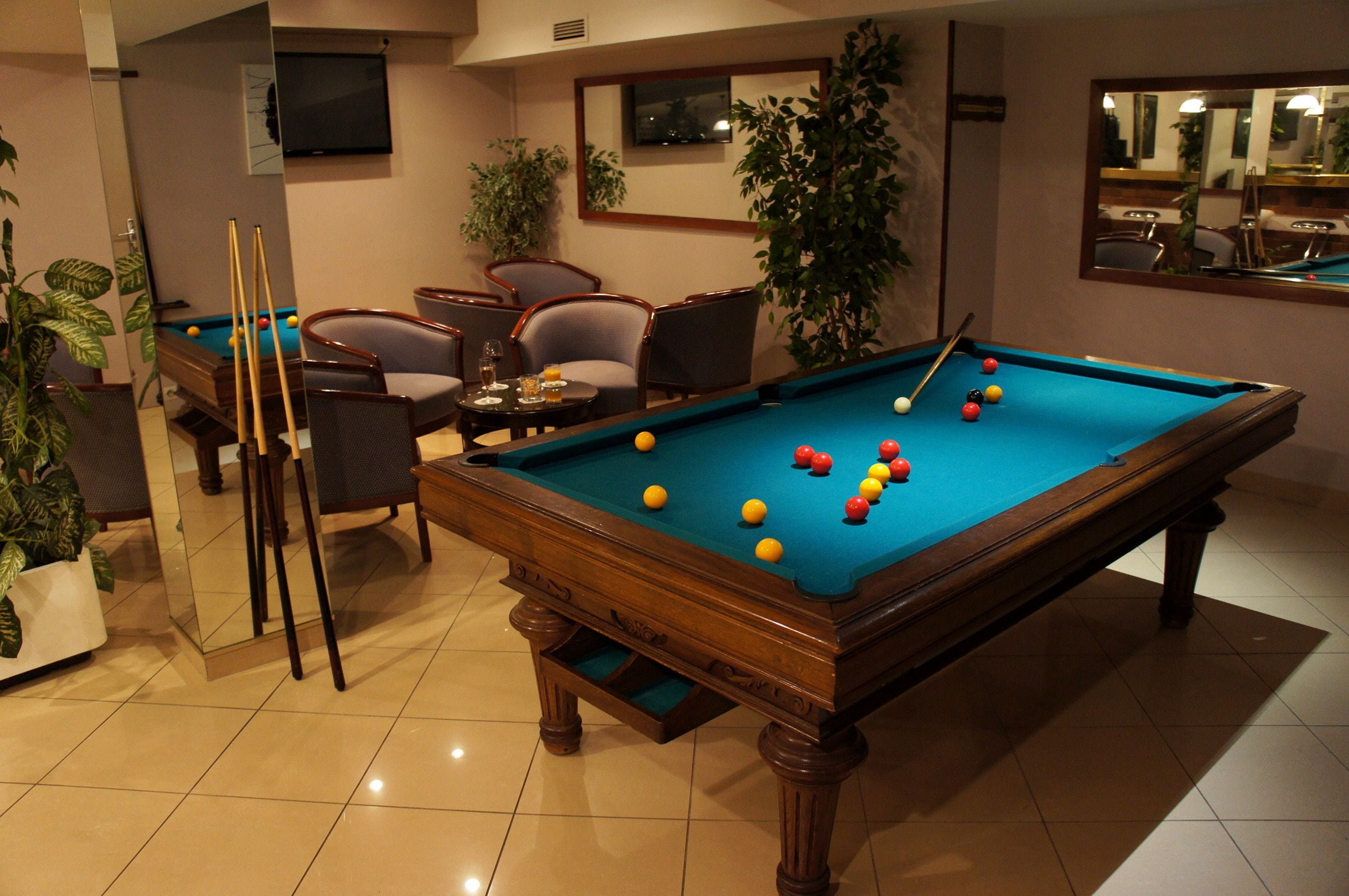 Una mesa de billar con bolas, una televisión y una zona de estar con sillas y una mesa.