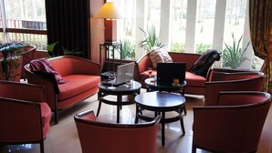 Uma sala de estar moderna com sofás vermelhos, um laptop sobre uma mesa e uma luminária.