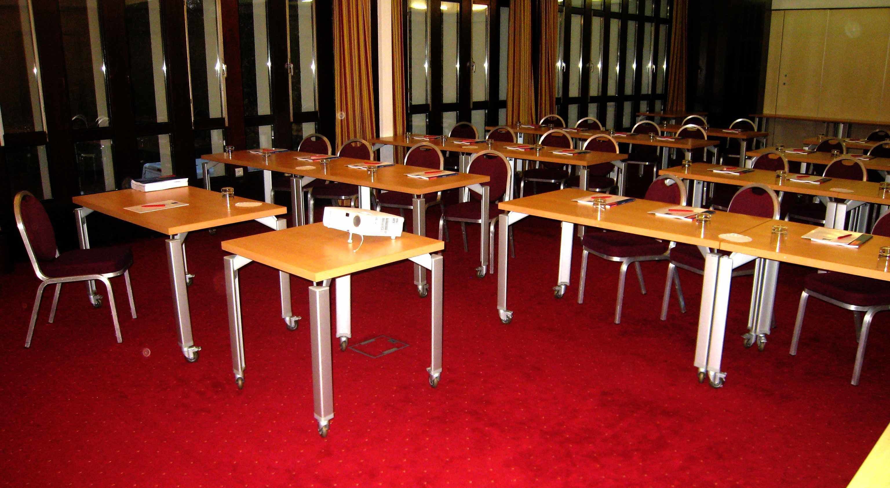 Ein Konferenzraum mit Reihen von Tischen und Stühlen, ausgestattet mit Namensschildern und Stiften.