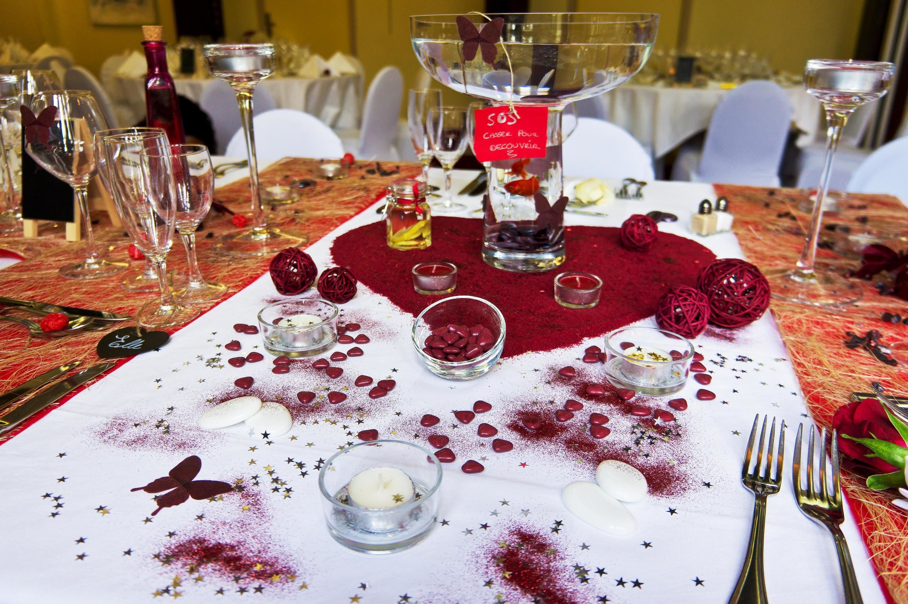A table set for a formal dining event with clear glassware, a central decorative bowl, and scattered rose petals.