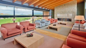 Un amplio salón con chimenea de piedra, varios sofás y un ventanal con vistas al exterior.