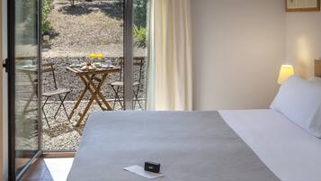 Een hotelkamer met een bed, een tafel met ontbijtartikelen en uitzicht op het buitengebied.