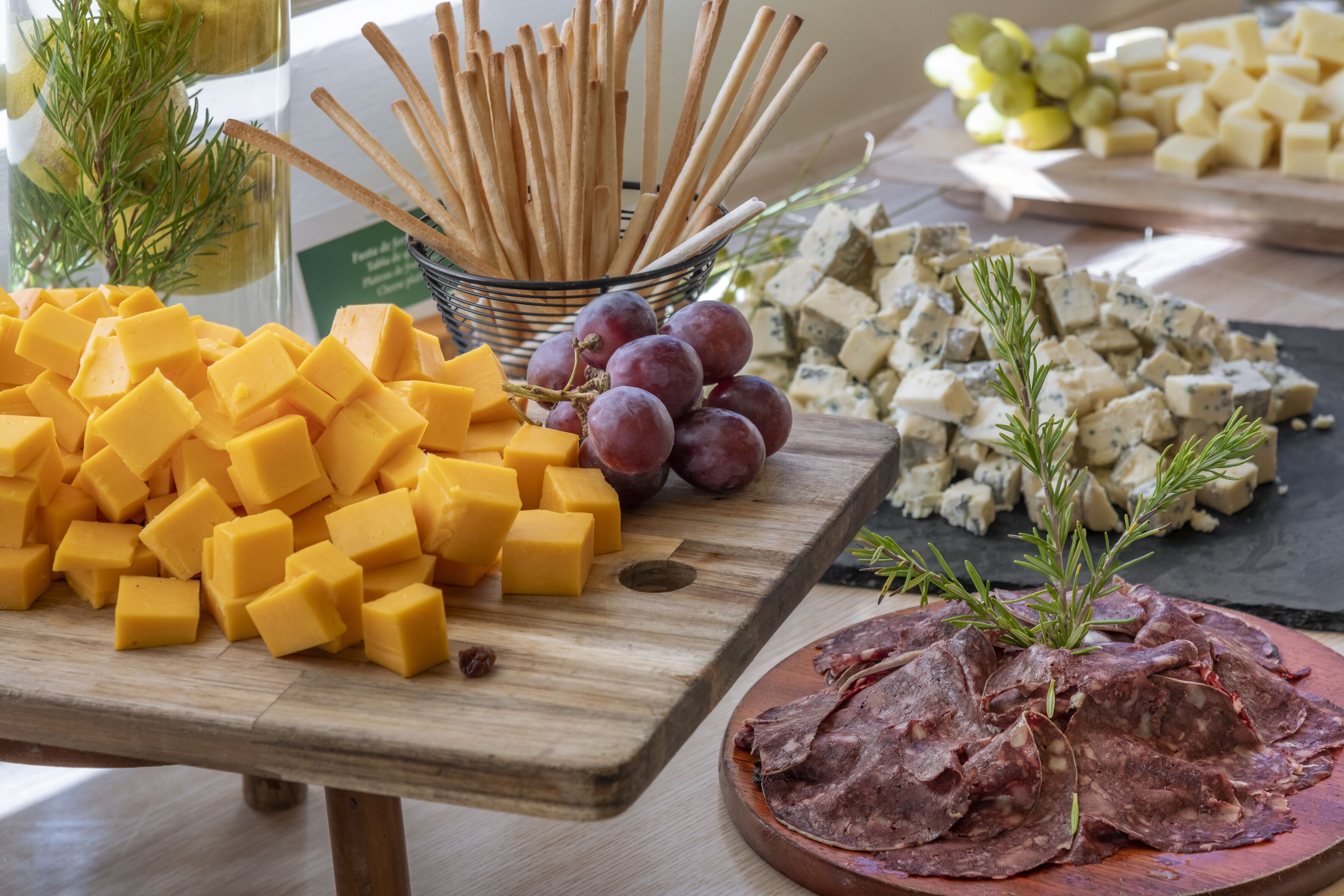 A variety of cheeses, grapes, and crackers on a wooden table.