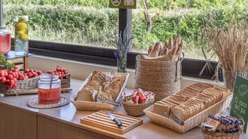 Un bufé de desayuno con panes, pasteles y frutas frescas.