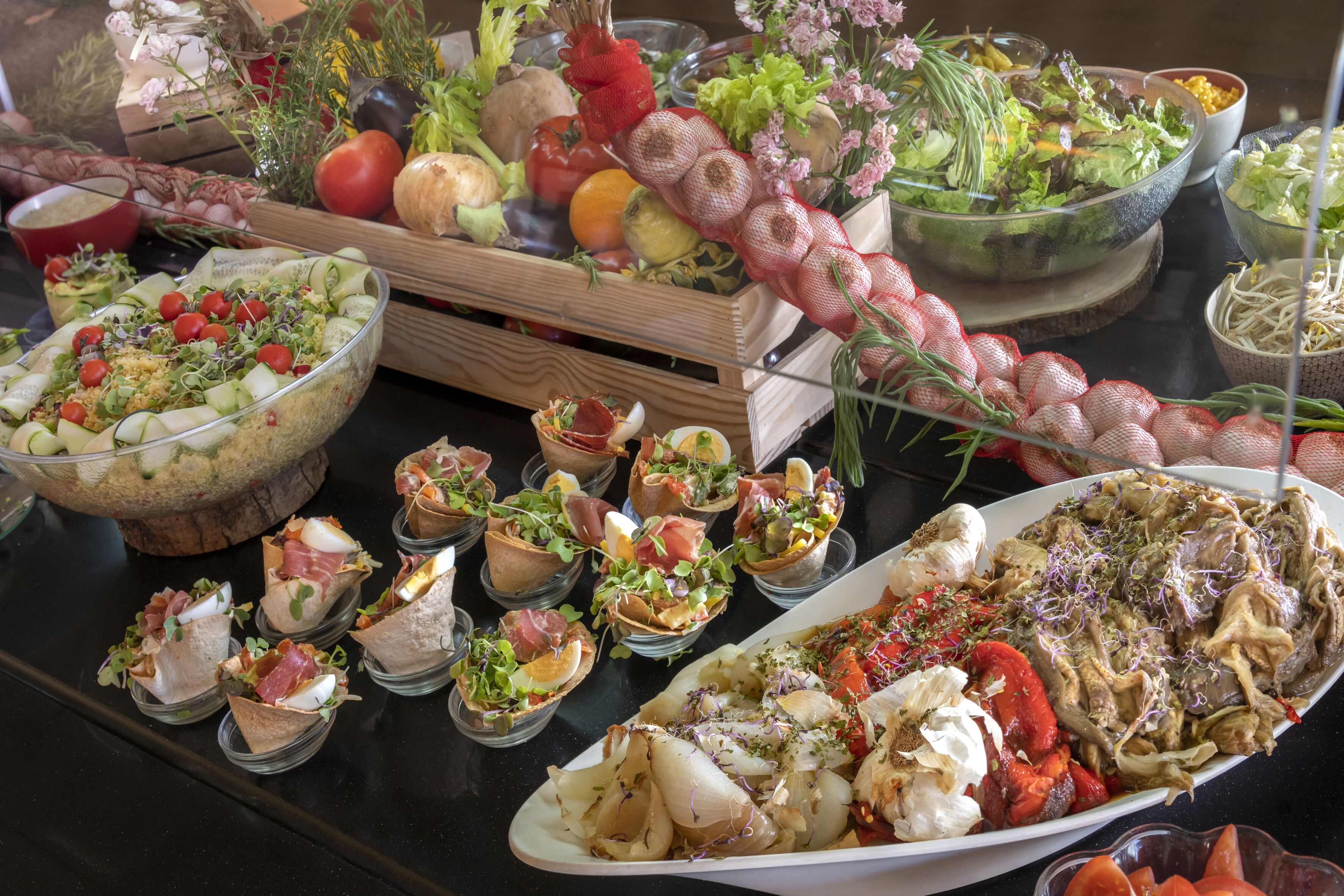 Un bufé con diversos platos, incluyendo ensaladas, carnes y verduras.