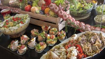 Un bufé con diversos platos, incluyendo ensaladas, carnes y verduras.