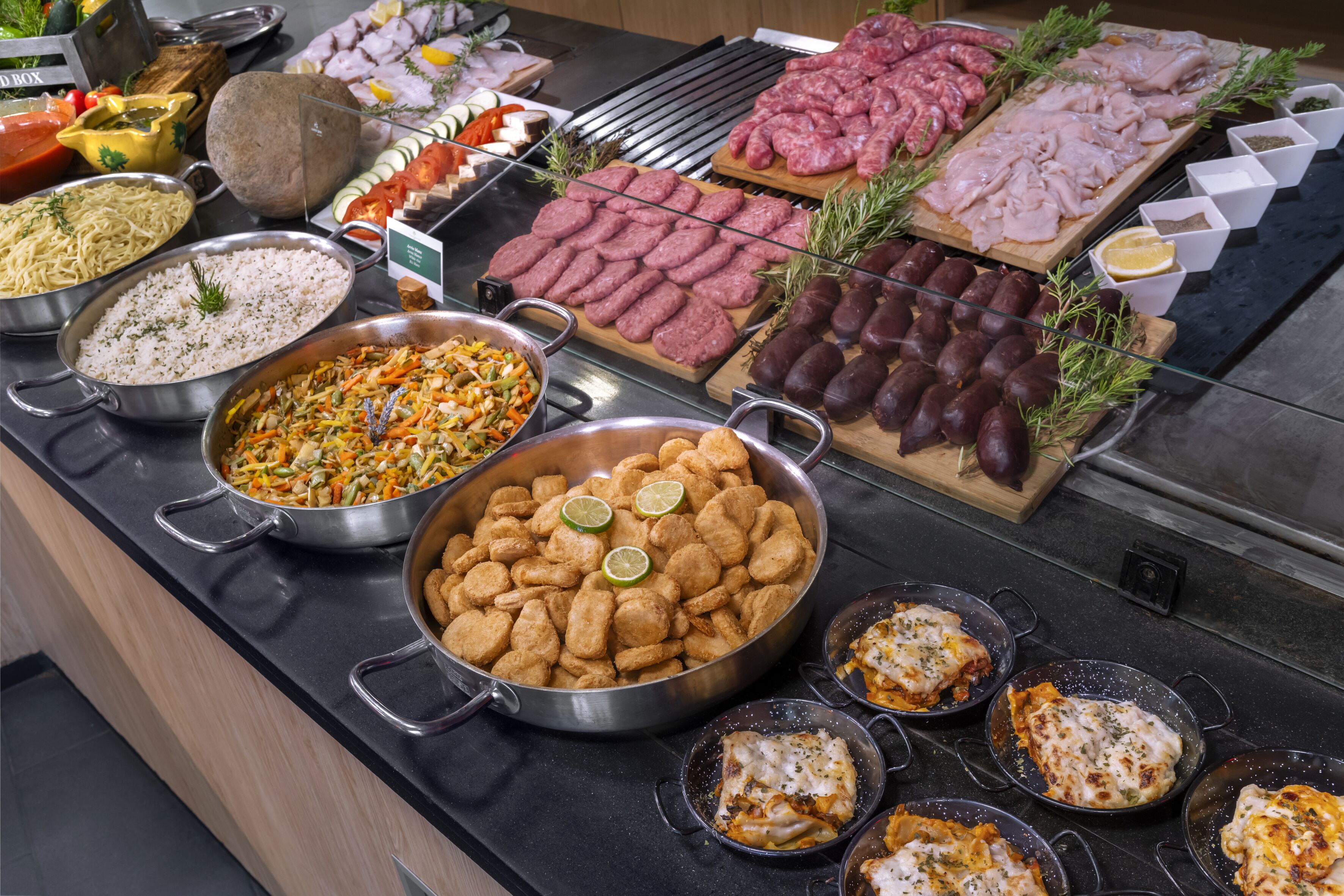 A buffet with various food items including meats, vegetables, and pasta dishes.