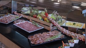 Un bufé con diferentes opciones de comida, incluyendo carnes, quesos y verduras.