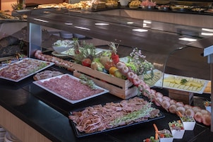 Un bufé con diferentes opciones de comida, incluyendo carnes, quesos y verduras.