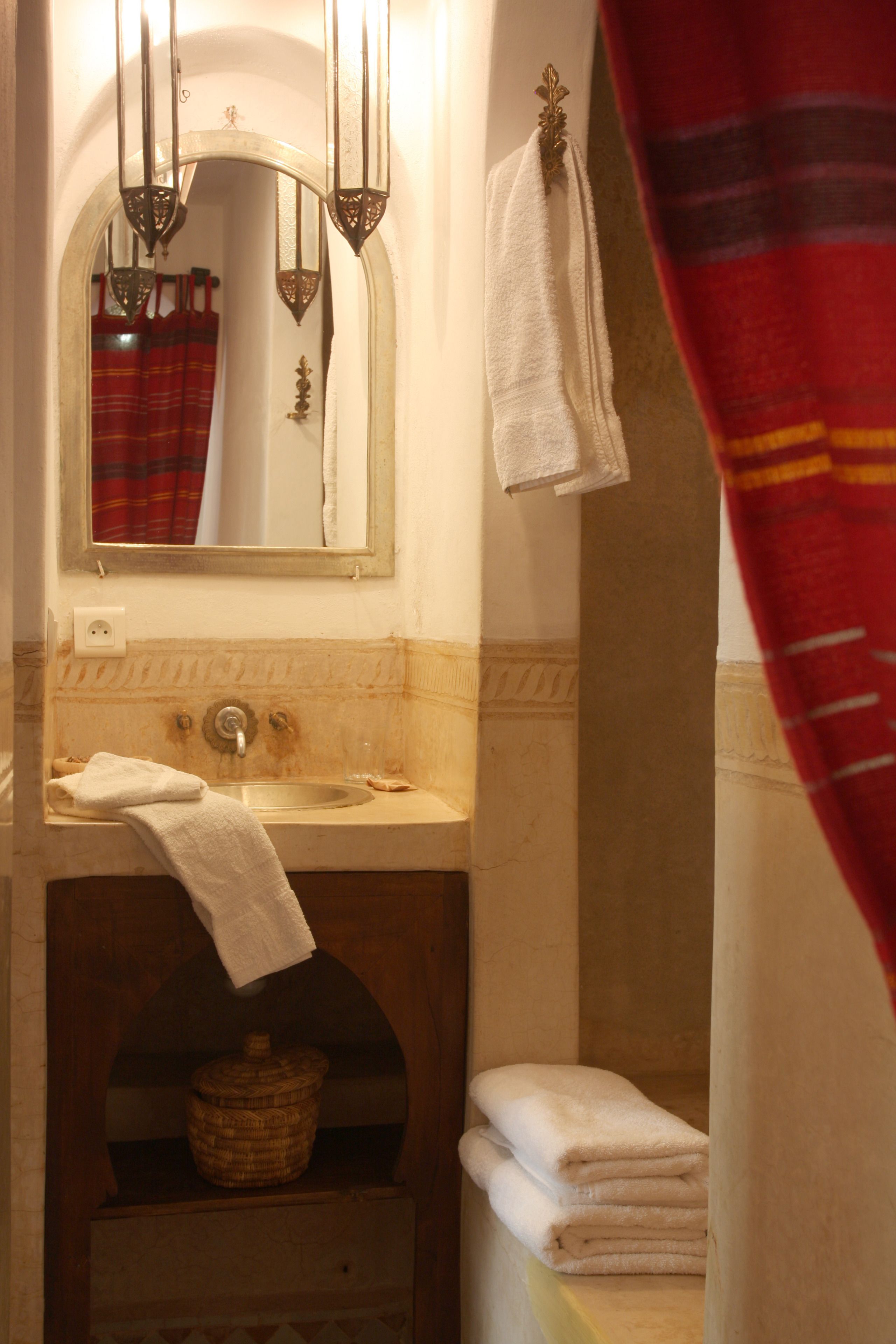 Un baño con lavamanos, espejo y perchero para toallas.