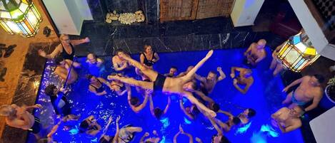 Un groupe de personnes se trouve dans une piscine, avec une porte en bois et un sol en marbre.