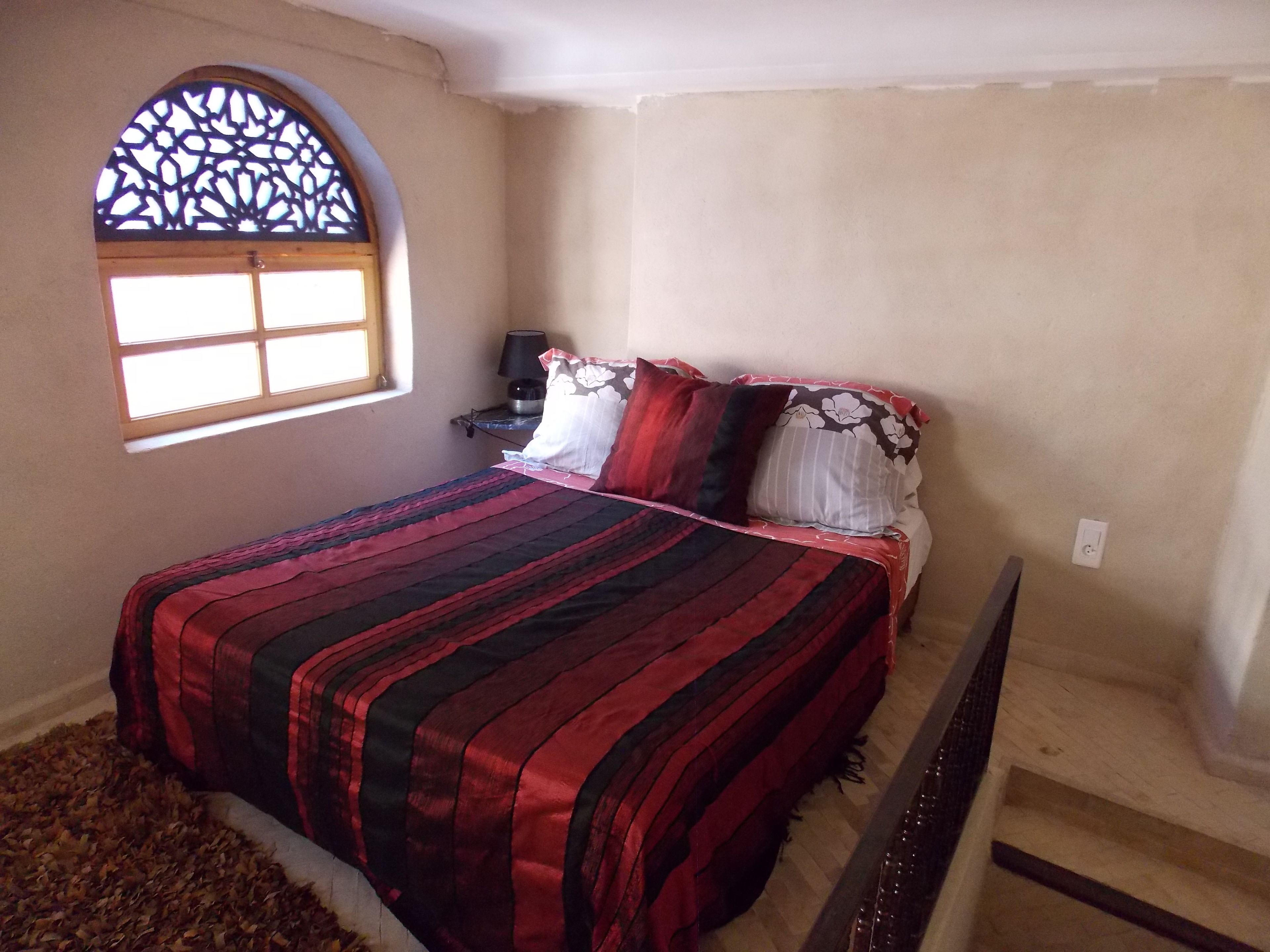 Une chambre à coucher avec un lit, une fenêtre et une table de chevet.