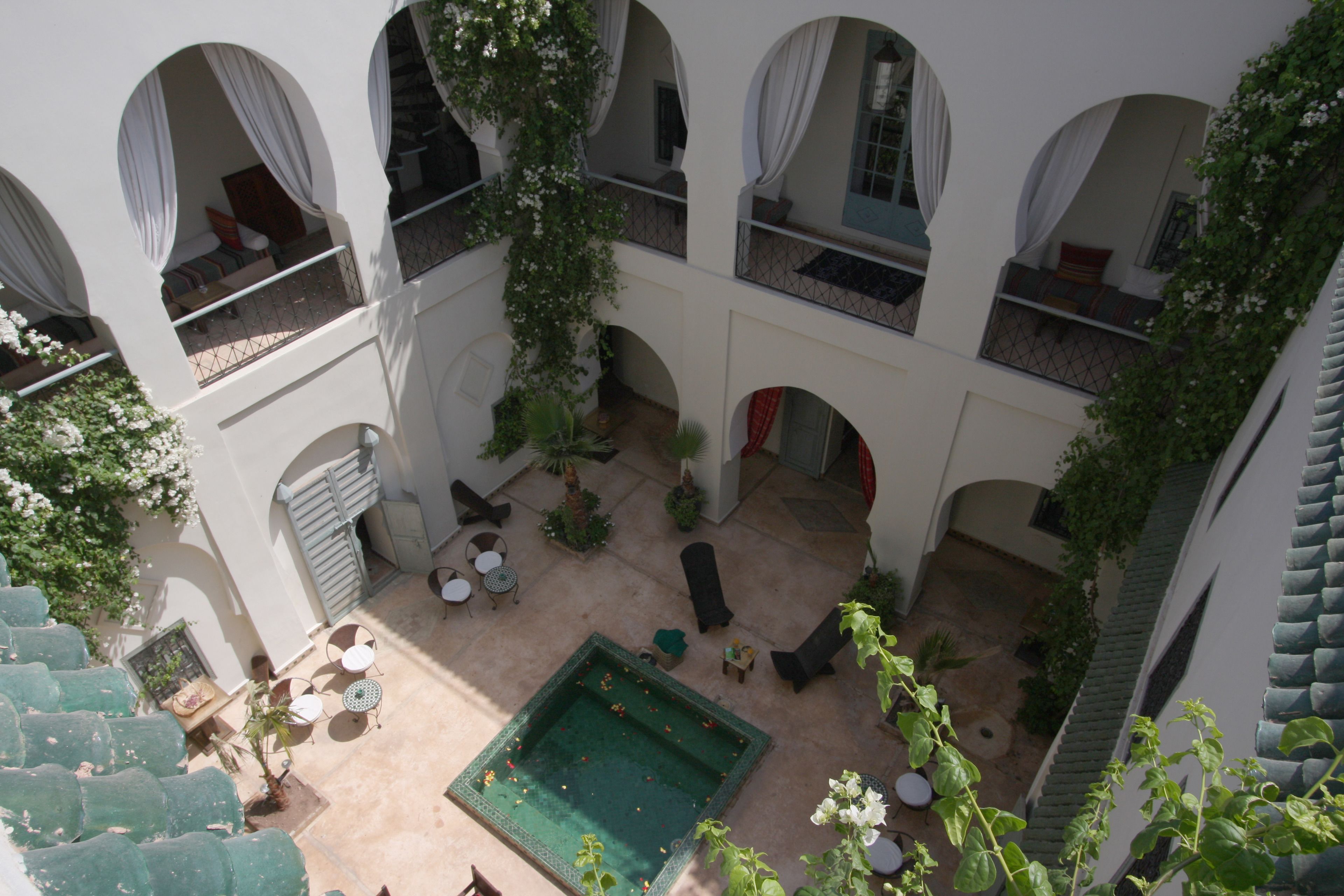 A courtyard with a swimming pool, outdoor seating, and multiple balconies with white curtains.