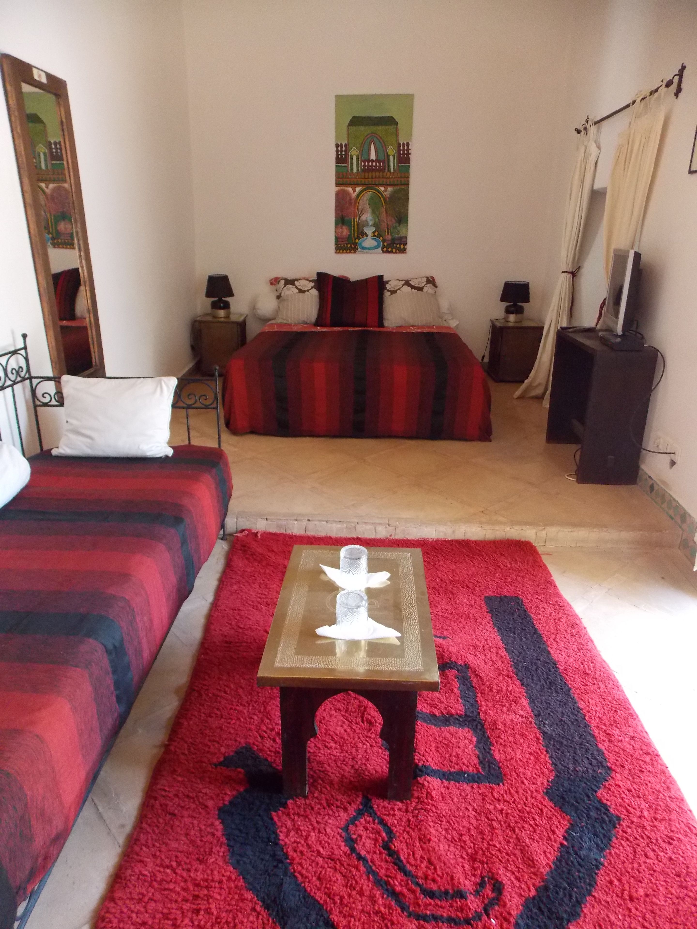 Habitación de hotel con dos camas, una mesita, un televisor y un cuadro en la pared.