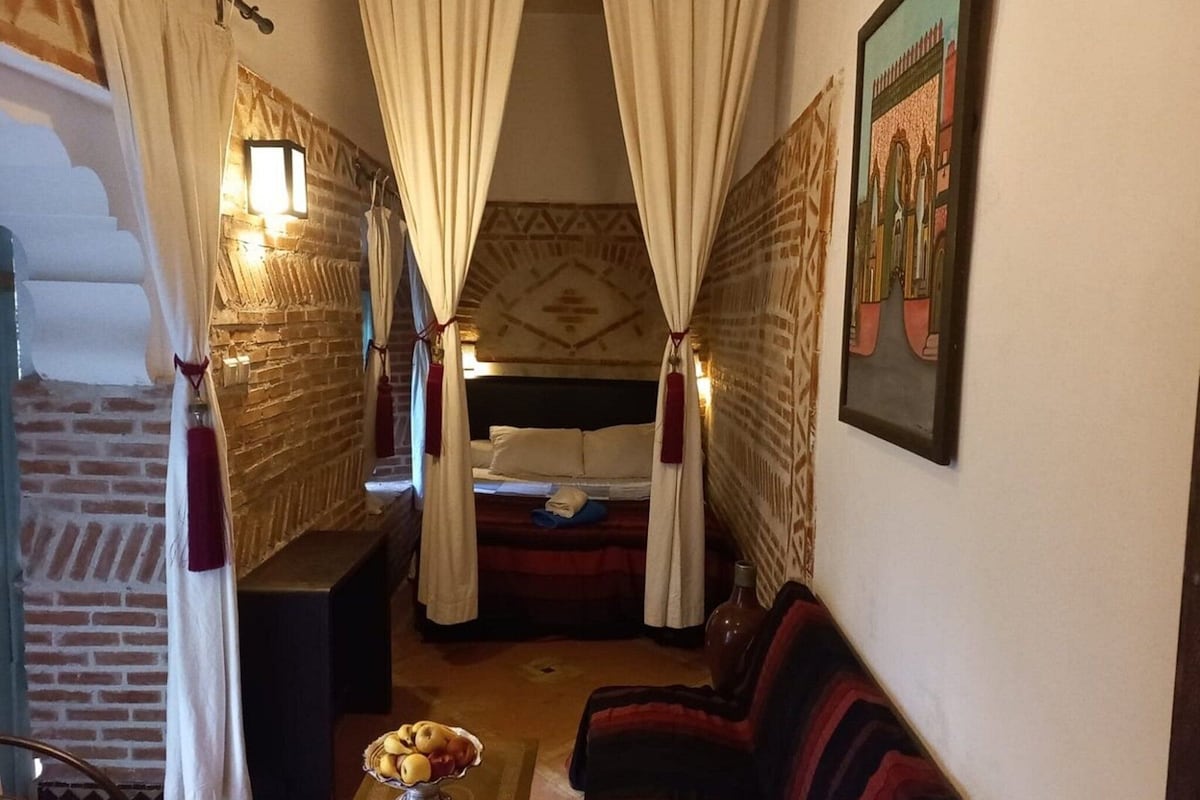 A cozy room with a bed, a small table with fruit, and a couch.