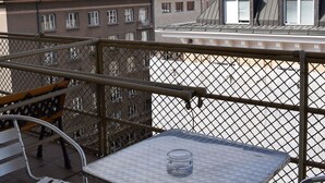 En balkon med et metaltabel og stole, der udover en by med bygninger og en kuppelstruktur.
