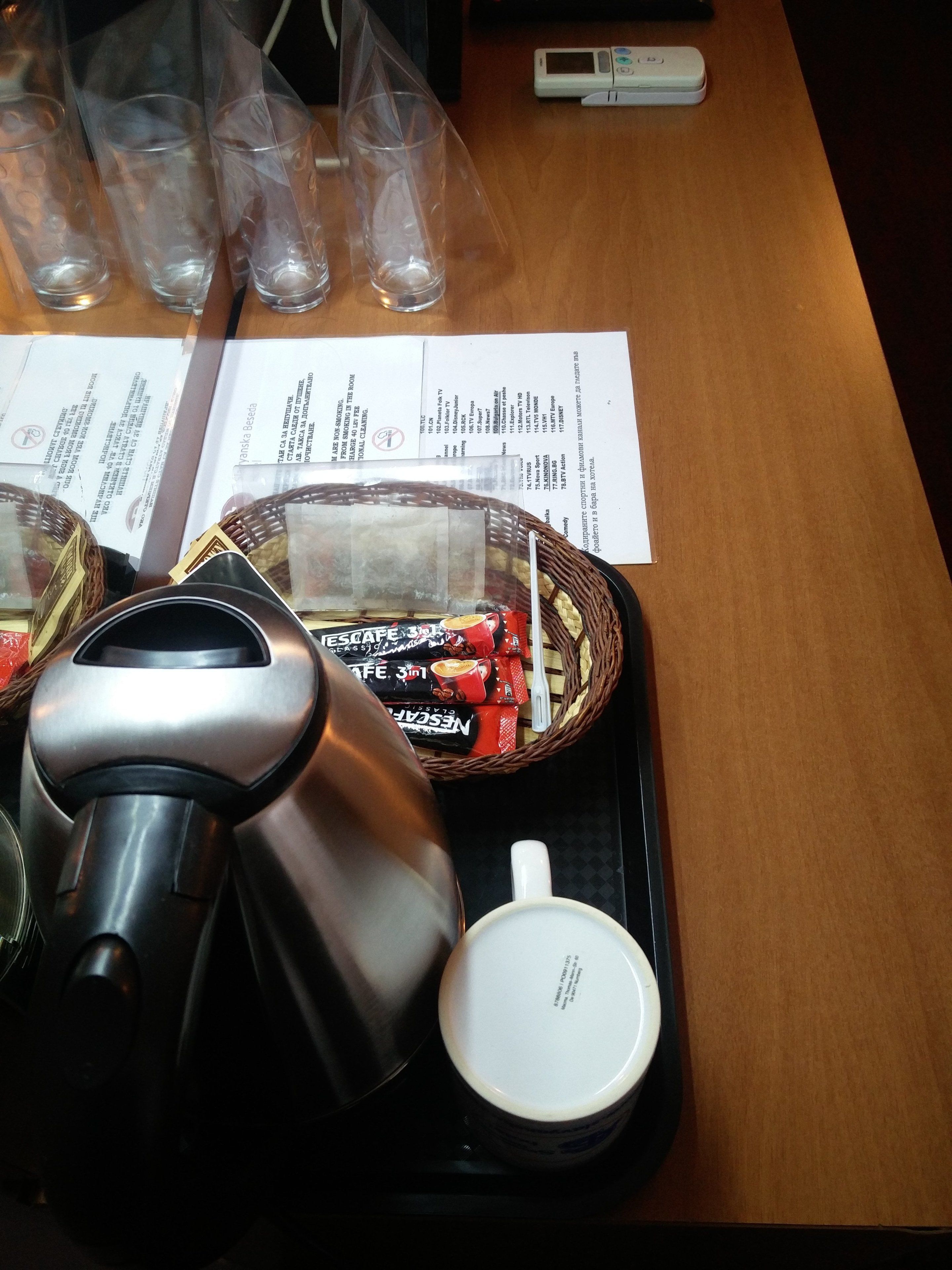 Une machine à café, une tasse, un panier rempli d’en-cas et un menu sur une table en bois.