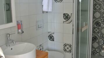 Une salle de bain avec un lavabo blanc, des toilettes et une douche à parois de verre.