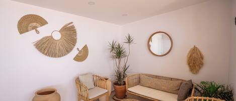 Una habitación con sofá, sillas, una mesa redonda y decoración en la pared.