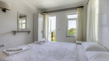 A hotel room with a large bed, a bedside table, a mirror, and a window with curtains.