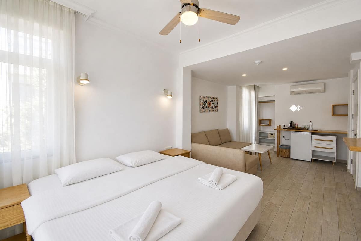 Una habitación de hotel con una cama grande, un escritorio, un sofá y una kitchenette.