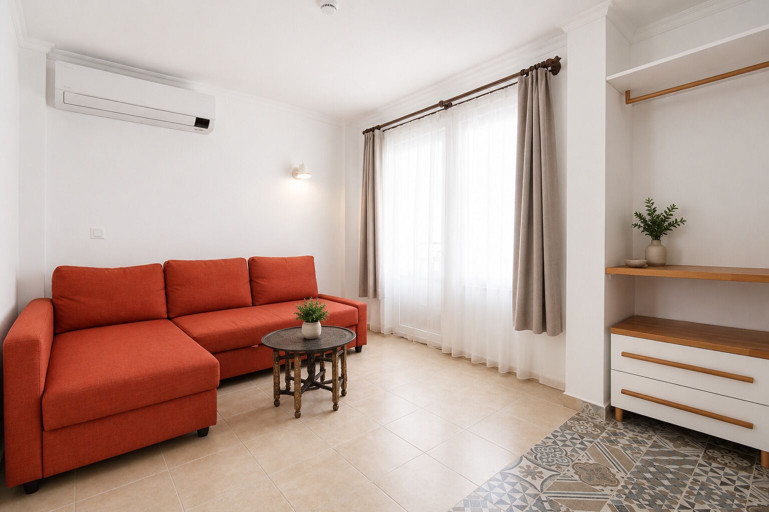 Una sala de estar moderna con un sofá, una mesita redonda con una planta, un aire acondicionado de pared, una ventana con cortinas traslúcidas y un estante de madera con una planta.