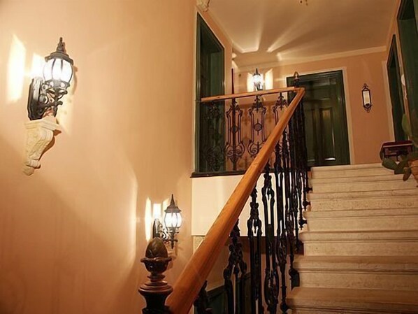 A staircase with ornate metal railings and wall-mounted lamps.