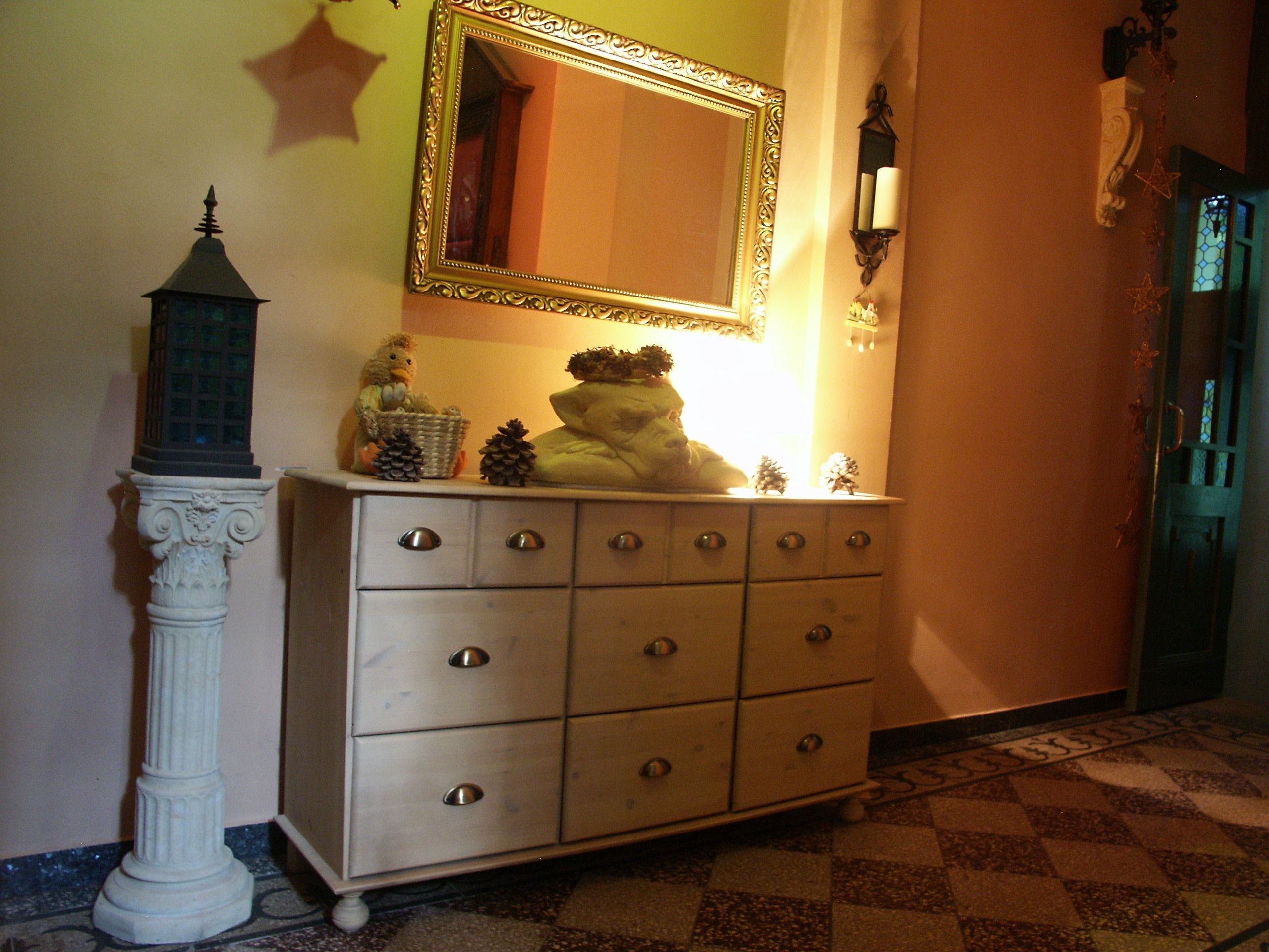 Een gang met een witte dressoir, een spiegel en een kleine sierlamp.