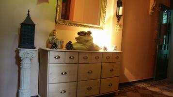 Een gang met een witte dressoir, een spiegel en een kleine sierlamp.