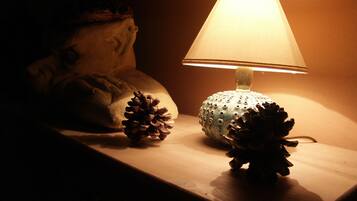 A lamp with a textured lampshade on a wooden surface, accompanied by two pine cones.