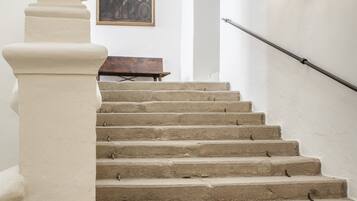 Una escalera con barandilla blanca, una lámpara de pared y una obra de arte enmarco.