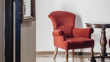 Una habitación con un sillón rojo, una mesa redonda de madera y un cuadro enmarcado en la pared.
