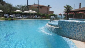 Una piscina con agua azul cristalina, rodeada de sillas de descanso y sombrillas.