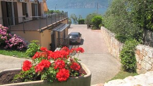 Una calle residencial con un coche estacionado al lado, un muro de piedra y montañas a lo lejos.