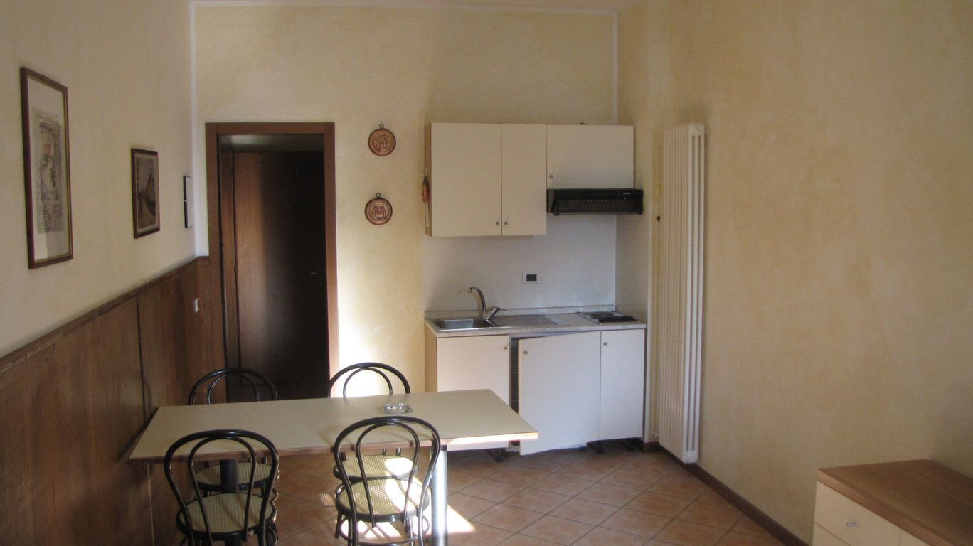 Una cucina compatta con tavolo e sedie, un piccolo bancone e un mobiletto.