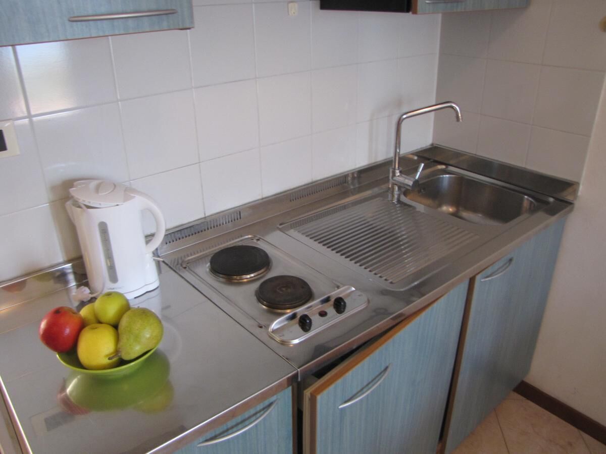 Una cocina compacta con un fregadero, estufa y un cuenco de fruta en la encimera.
