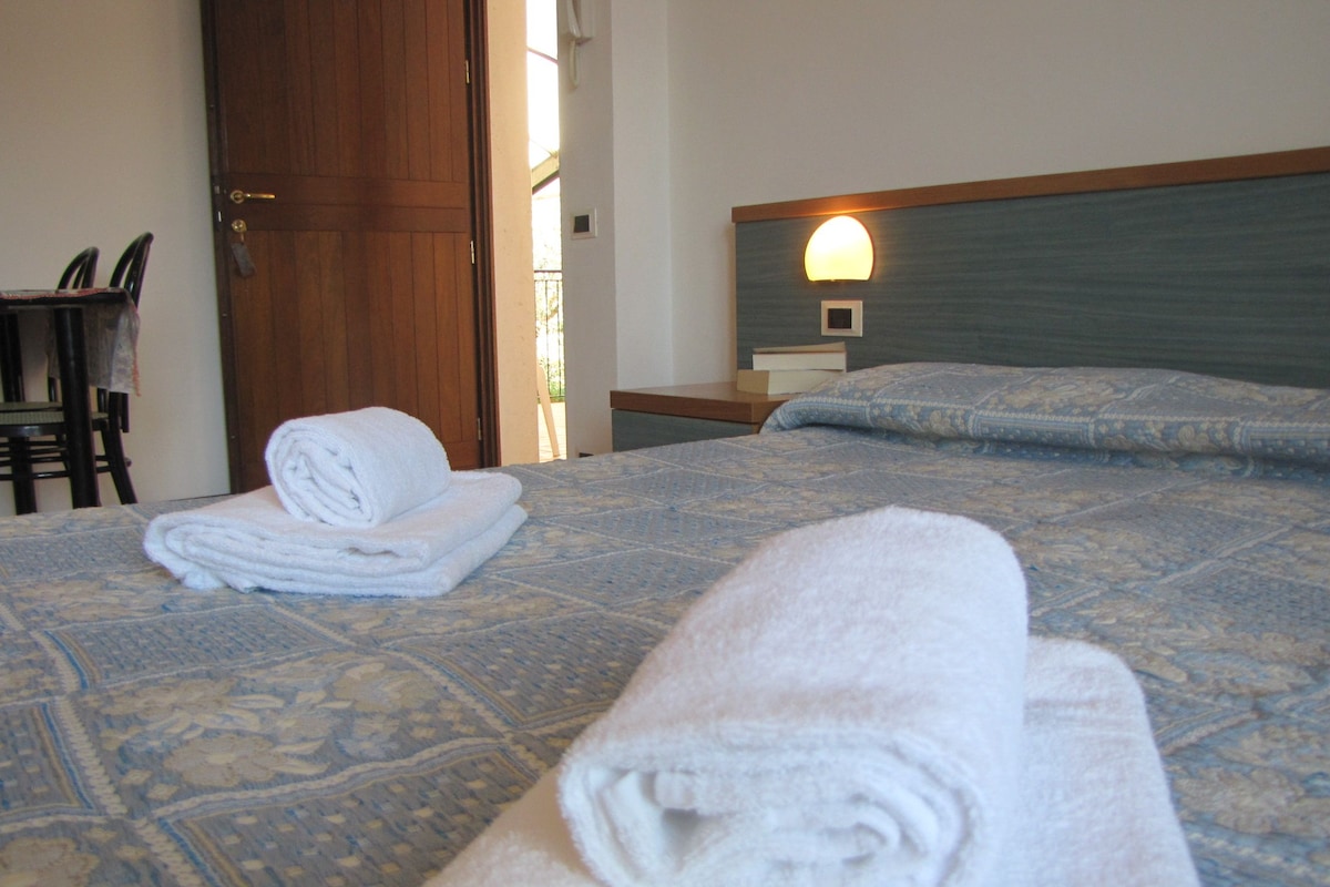 A hotel room with a bed, a nightstand, a chair, and a door.