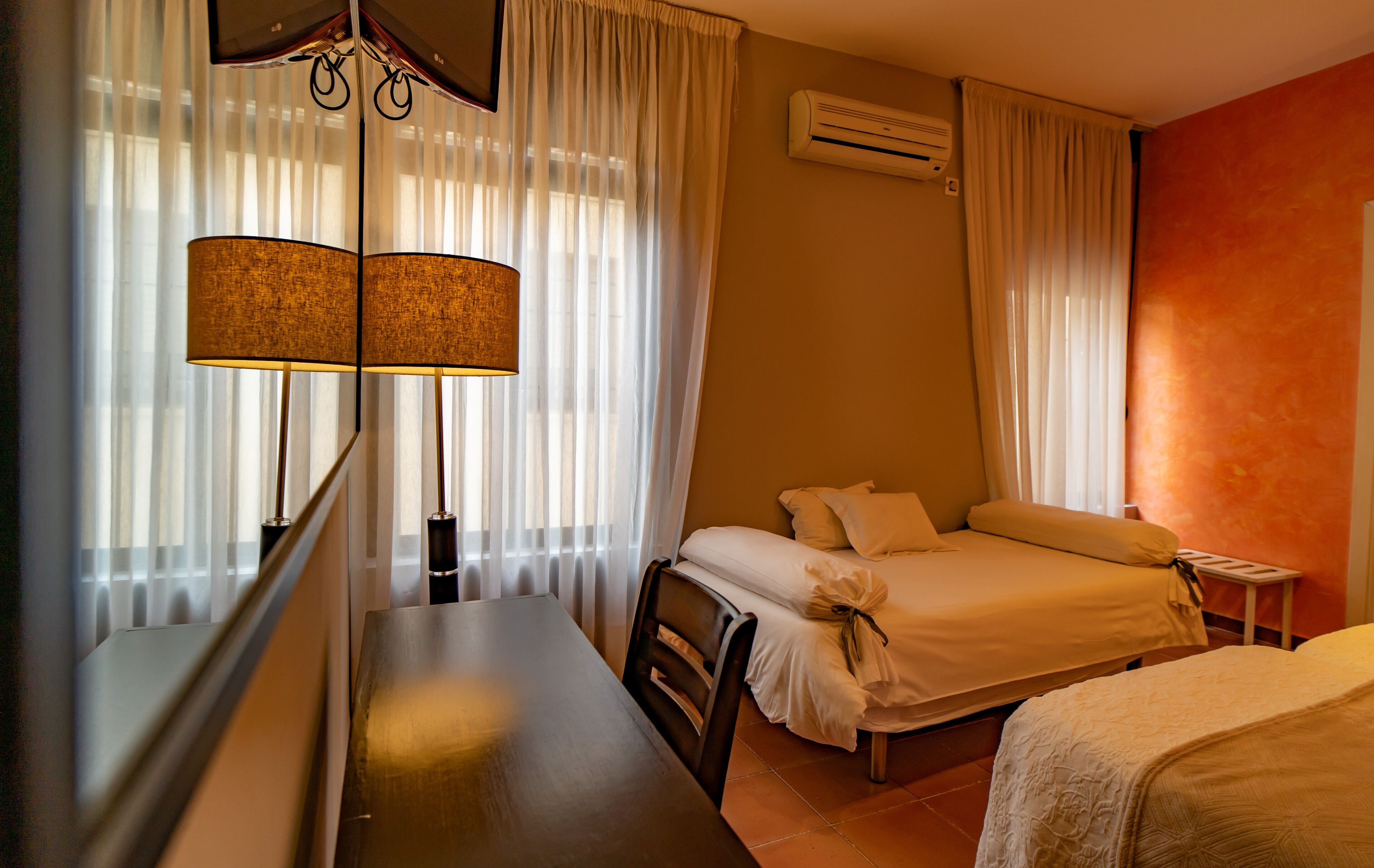 A hotel room with a bed, a desk, and a lamp.