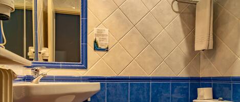 A bathroom with a sink, toilet, and mirror.