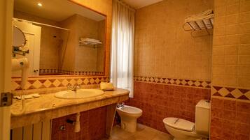 Un baño con dos lavamanos, un bidé, un inodoro y una ducha.