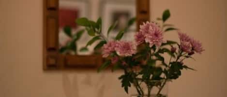 A wooden dresser with a vase of pink flowers on top.