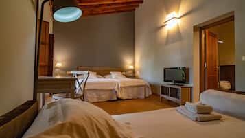 Habitación de hotel con dos camas, televisor, escritorio con lámpara y techo de madera.